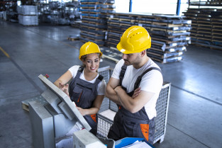 Industrial employees with yellow hardhat operating machines at production line using new software computer